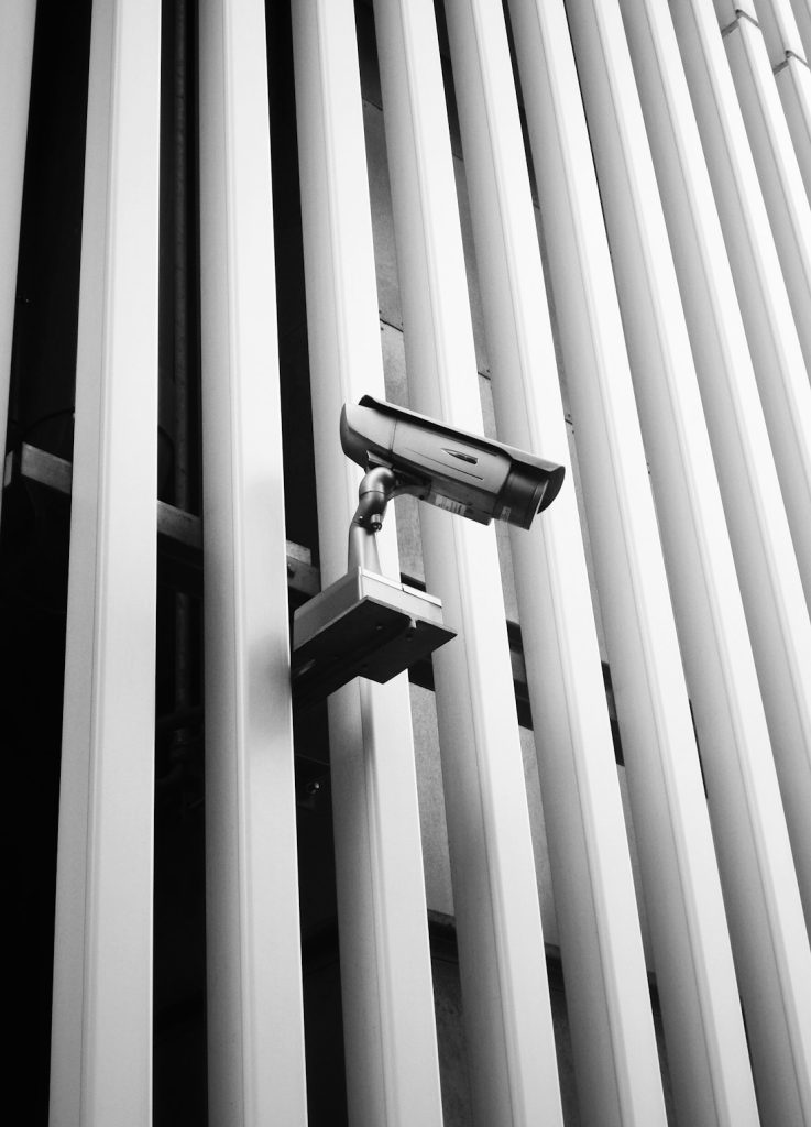 Security camera mounted between white architectural fins
