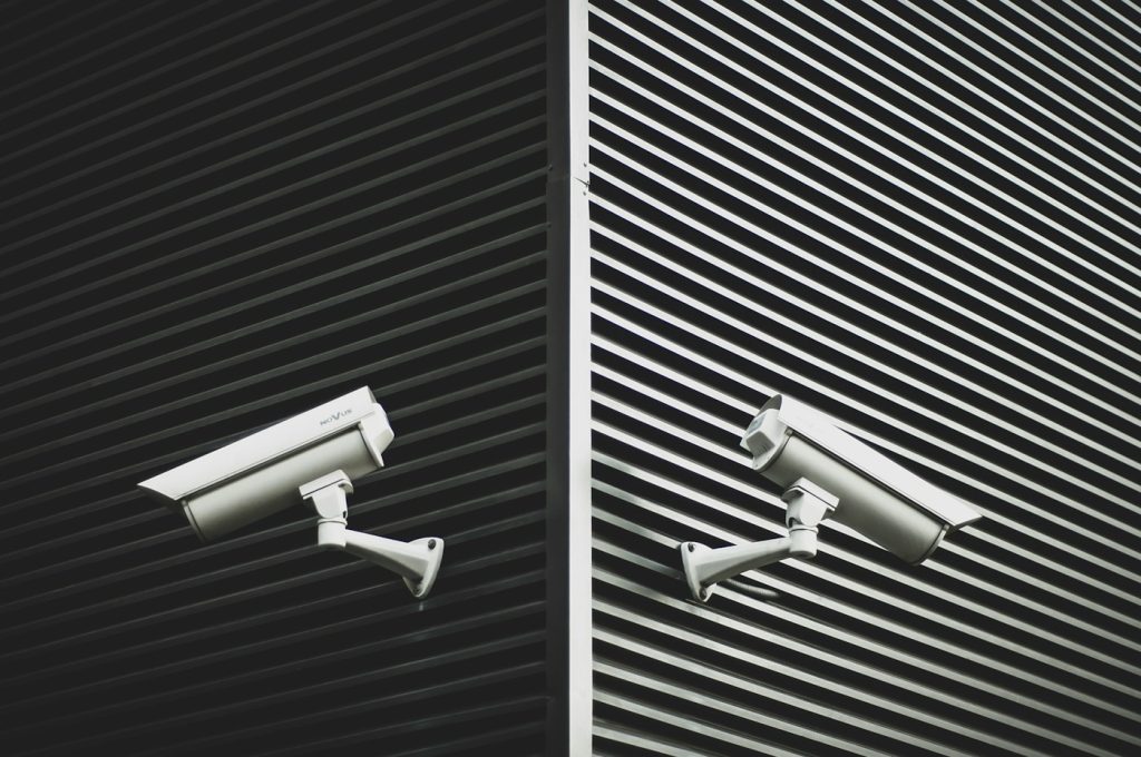 Two CCTV cameras mounted on a contemporary striped facade